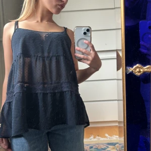 Mörkblått Linne från Hollister - Säljer ett mörkblått linne från Hollister med tunna axelband och broderidetaljer. Toppen har ett prickigt mönster och spetsdetaljer som ger en supersöt touch. Perfekt för layering eller över en bikini🩷🙌🏻