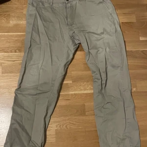 Beige chinos - Snygga beige chinos med normal passform. Perfekta för en avslappnad stil. De har en klassisk design med knappar och dragkedja framtill.