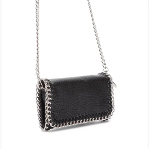 tiamo väska - Snygg svart axelväska i skinn med coola kedjedetaljer runt kanterna. Väskan har en stilren design och en kedja som axelrem, perfekt för att ge din outfit en edgy touch. Tiamo liten väska köpt på scorett💝