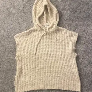 Säljer en mysig beige stickad ärmlös hoodie från Zara. Perfekt för lager-på-lager-stil med en skön huva och dragsko. Passar utmärkt för kyliga dagar när du vill ha något bekvämt och stilrent. 🧶