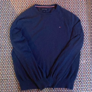 Blå tröja från Tommy Hilfiger - Säljer en stilren blå tröja från Tommy Hilfiger med rund halsringning. Den är i toppskick👑(100% bomull👔). Hör av dig vid minsta fråga✌️