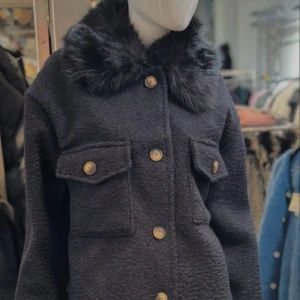 Svart jacka med fuskpäls - Snygg svart jacka med fuskpälsdetaljer på kragen och knappar framtill. Jackan har två bröstfickor med lock och en stilren design som passar perfekt för kyligare dagar. Original pris 1200kr är köpt på Chelsea som bara finns på Kungsgatan i Göteborg. 