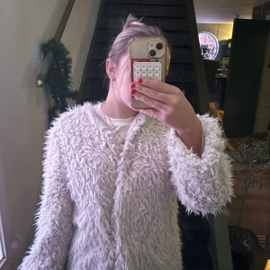 Beige pälsjacka - Säljer en fluffig beige pälsjacka med lång ärm. Jackan har en quiltad insida och är perfekt för kyligare dagar. Den är stilren och lätt att matcha med olika outfits.