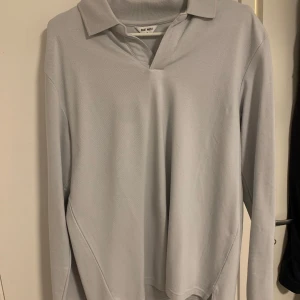 Ljusgrå pikétröja från Uniqlo - Säljer en stilren ljusgrå pikétröja från Uniqlo. Tröjan har långa ärmar och en klassisk krage. Perfekt för en avslappnad men ändå snygg look.