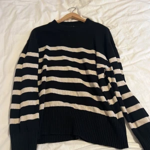 Svart och vit randig tröja från Gina Tricot - Säljer en snygg svart och vit randig tröja från Gina Tricot. Tröjan är stickad med långa ärmar och har en bekväm passform. Perfekt för kyligare dagar.