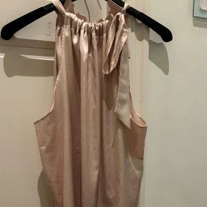 Champagnefärgad halterneck topp - Assnygg topp som jag köpte i en butik i Sturegallerian i stockholm, nypris ligger på  ca 700kr och den är sparsamt använd. Det är onesize