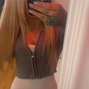 Grå ribbad kofta med dragkedja - Snygg grå ribbad kofta med dragkedja framtill. Perfekt för lager-på-lager och ger en stilren look. Koftan har långa ärmar och en croppad passform.