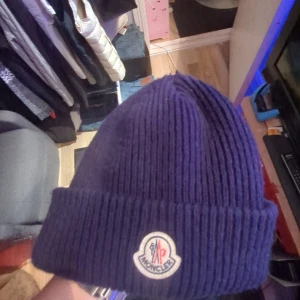 Moncler mössa  - Snygg mörkblå ribbad mössa från Moncler med broderad logga framtill. Perfekt för kyliga dagar och ger en stilren look. Använd 2 gånger 