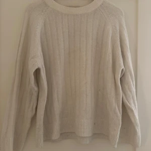 Vit stickad tröja - Mysig vit stickad tröja med ribbade detaljer. Har en liten fläck på armen jag inte lyckats få bort och är även rätt använd och nopprig men inget man tänker på! skriv för närmre bilder 🤍🤍 storlek xs men passar även s-m
