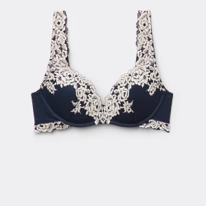 Mörkblå bh med spetsdetaljer - Elegant mörkblå bh med vackra vita spetsdetaljer. Den har en klassisk design med justerbara axelband och en bekväm passform. Använd fåtal gånger och är i super skick.