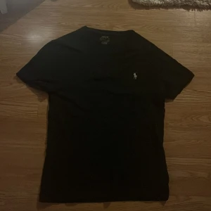 Svart t-shirt från Ralph Lauren - Snygg svart t-shirt från Ralph Lauren med broderad logga på bröstet. Den har en slim fit passform och är tillverkad i ett mjukt material. Perfekt för en stilren look. Väldigt bra skick passar S och XS! Säljer denna då den är för liten och skulle passa på längden om man är mellan 170-175