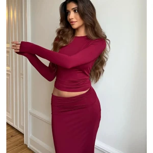 Mörkröd långärmad topp - Snygg mörkröd långärmad topp med tight passform. Perfekt för en stilren look, kan matchas med både kjol och jeans. Enkel design som passar till många tillfällen. Tagg kvar, ej använt.