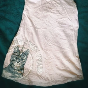Rosa linne med kattmotiv - Säljer ett rosa linne med ett gulligt kattmotiv och texten 'Wish I was a unicorn'. Perfekt för en avslappnad stil med en rolig twist. Linnet har en rund halsringning och ärmlös design.