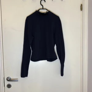 Marinblå långärmad polotröja - Snygg och stilren matinblå polotröja med långa ärmar. Perfekt för kyligare dagar och enkel att matcha med olika outfits. Ett måste i garderoben för en klassisk look.