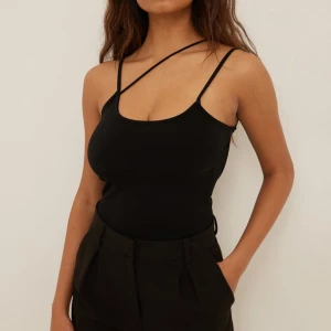 Svart ärmlös topp med öppen rygg - Snygg svart ärmlös topp från nakd med smala axelband och öppen rygg. 