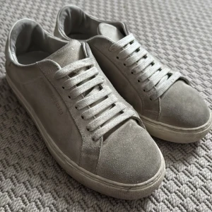 Beige sneakers från Axel Arigato - Snygga beige sneakers från Axel Arigato i mocka med klassisk snörning. Perfekta för en stilren look.
