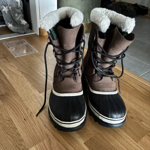 Bruna vinterkängor med foder - Säljer ett par robusta bruna vinterkängor med vit foder och svart nederdel. Kängorna har snörning och är perfekta för kalla dagar. De har en slitstark sula och är designade för att hålla fötterna varma och torra. Bara testad råka ta bort etiketter så kunde ej skicka tillbaka. Nypris 2199kr