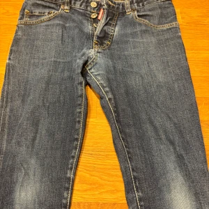 Blå jeans från DSQUARED2 - Snygga blå jeans från DSQUARED2 med gul text 'ICON' på bakfickan. Klassisk femficksdesign med dragkedja och knapp. Perfekta för en trendig look.