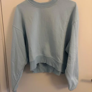 Ljusblå sweatshirt från Bershka - Säljer en ljusblå sweatshirt från Bershka. Tröjan har en avslappnad passform med långa ärmar och ribbade muddar vid ärmslut och nederkant. Tröjan har en liten defekt som inte syns på långt håll (se bild 4) köptes secondhand och va i mycket bra skick då. Säljer för att den inte kommer till användning!💕