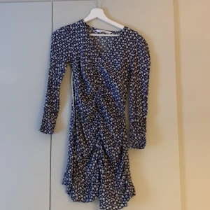 Blommig omlottklänning - Charmig blå omlottklänning med vita blommor. Klänningen har långa ärmar och en smickrande omlottdesign som ger en fin siluett. Perfekt för vår och sommar! Dennna klänning är ifrån Mango❤️