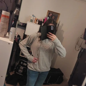 Grå hoodie med text - Säljer en grå hoodie med texten 'WHAT EVER' tryckt på framsidan. Tröjan har långa ärmar och en klassisk huva. Perfekt för en avslappnad stil.