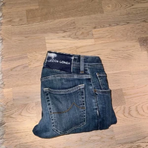Ett par tvär feta Blå jeans från Jacob Cohen - Snygga blå jeans från Jacob Cohen med slim passform. De har klassiska fem fickor och knappar med märkets logga. Perfekta för en stilren look. Nypris 5449- mitt pris 1500- kan gå ner i pris vid snabb köp💯