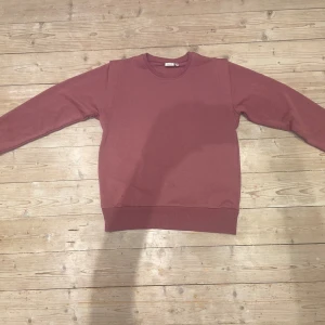 Rosa tröja från Name It - Säljer en enkel och stilren rosa tröja från Name It. Tröjan har långa ärmar och en rund halsringning den har även en liten ”spets” där armarna fäster, perfekt för en avslappnad look. Passar ungdomar i åldern 13-14 år.