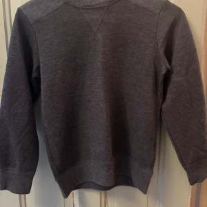 Mörkgrå cardigan - Säljer en stilren mörkgrå cardigan med långa ärmar och ribbade muddar. Aldrig använd, storlek 146