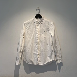 Vit skjorta från Ralph Lauren - Säljer en klassisk vit skjorta från Ralph Lauren med broderad logotyp på bröstet. Skjortan har långa ärmar och knappar framtill. Perfekt för en stilren look. Priset kan diskuteras 😀