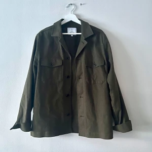 Olivgrön overshirt med knappar - Snygg olivgrön overshirt med knappar och två bröstfickor. Perfekt för lager-på-lager-stil. Långärmad design med klassisk krage. 