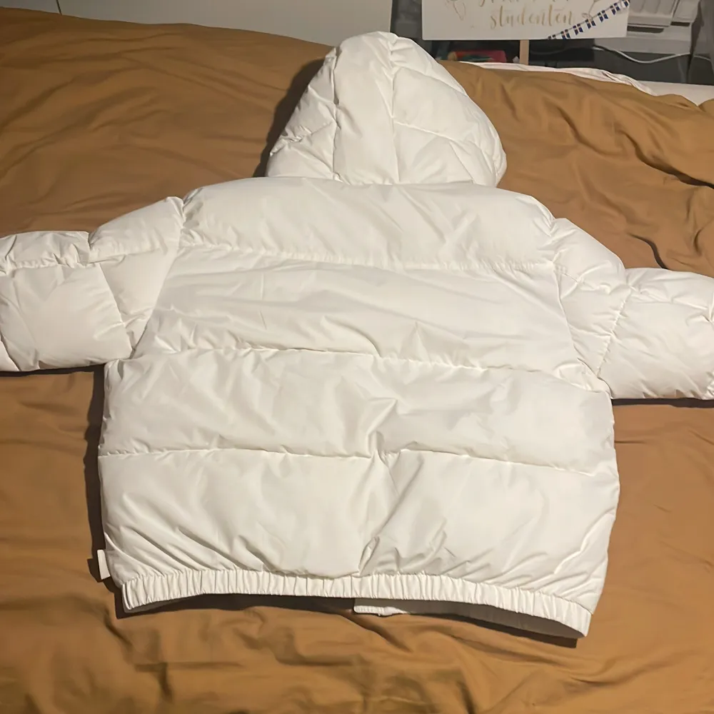 Säljer en snygg vit pufferjacka från Bershka. Jackan har en mysig huva och dragkedja framtill. Perfekt för kyliga dagar med sin vadderade design. Den är både stilren och praktisk. Jackan har två innerfickor på varsin sida. Använd ungefär 3 gånger, den värmer riktigt bra och passar till det mesta, det är en stor modell som baggyjeans fast för jacka. Köparen står för frakt. Takit.