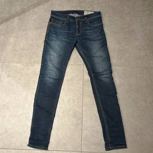 Diesel jeans - Snygga blå jeans från Diesel med en slim passform. De har klassisk femficksdesign och orange sömmar som ger en cool kontrast. Perfekta för en stilren look.