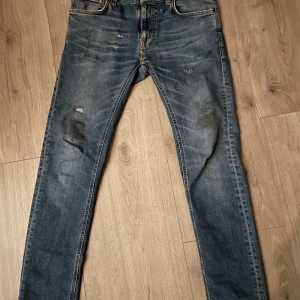Blåa Nudie Jeans. - Säljer dessa slim fit jeans från ”Nudie Jeans”. Jeansen har snygga slitringar på framsida men inga ytligare defekter förutom att lappen på baksidan är något skrynklig. Se sista bilden. Nypris på dessa jeans är omkring 1400kr och det är ej hugget i sten på denna annons. Har ni fler frågor är det bara att skriva🙏🙌