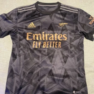 Arsenal borta ställ 22/23 - Tja! Säljer den feta Arsenal borta ställ 22/23 i en väldigt nice colour way❗️| Skick: 9,5/10! Otroligt bra skick, har bara använts 1-3 gånger förr |Storlek: S | Ny pris ca 1500kr 💵| Färg: Mörk grå 🩶| Tillbehör: Tyvärr inga tillbehör är med denna varan 🙁| Hör av er för mer information! | Allt gott 😉👊