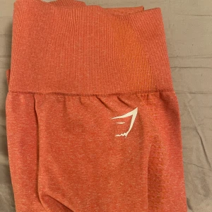 Orange leggings från Gymshark - Snygga orange leggings från Gymshark med hög midja och ribbad detalj. Perfekta för träning med en tight passform som ger bra stöd. 