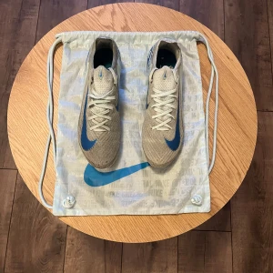 Nike mercurial Vapor 16 ag pro blåa, strl 42 26,5 cm  - Snygga fotbollsskor från Nike i beige med blå detaljer. Skorna har snörning och en slitstark sula med dobbar för bra grepp på planen. Perfekta för fotbollsspelare som vill ha stil och funktion.
