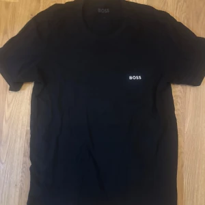 Svart t-shirt från Boss - Snygg svart t-shirt från Boss med enkel design och liten logga på bröstet. Perfekt för en stilren look. Passar s