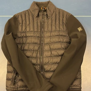 Rock And Blue - Cardigan - Svart cardigan från Rockandblue med quiltad design och dragkedja framtill. Jackan har långa ärmar och en diskret logga på ärmen. Perfekt för kyligare dagar. Sitter mycket bra på mig, 189cm.