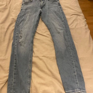 Blå jeans från Tommy Hilfiger - Snygga blå jeans från Tommy Hilfiger med en klassisk straight passform. De har en lätt slitning på framsidan och är perfekta för en avslappnad stil. Midjan är midwaist och de har en dragkedja.
