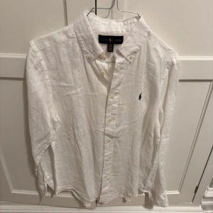 Vit linneskjorta från Ralph Lauren - Säljer en stilren vit skjorta från Ralph Lauren i linne. Skjortan har långa ärmar och knappar framtill. Perfekt för en klassisk och avslappnad look.