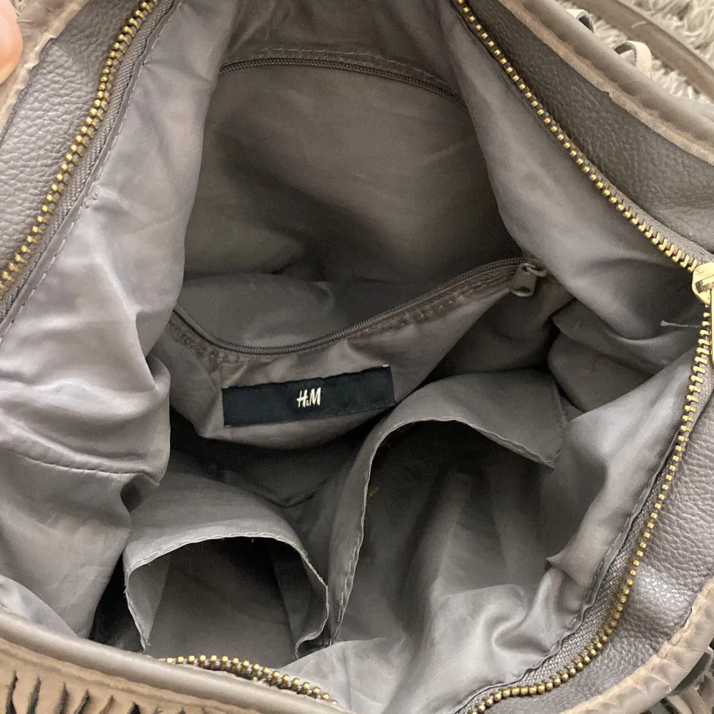 Snygg mörkgrön axelväska från H&M med långa fransar och dragkedja. Rymmer ganska mycket samt har flera fack. Laukut & Käsilaukut.
