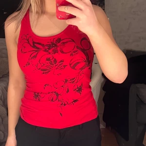 Röd linne med svart mönster - Snyggt rött linne med ett dekorativt svart mönster framtill. 