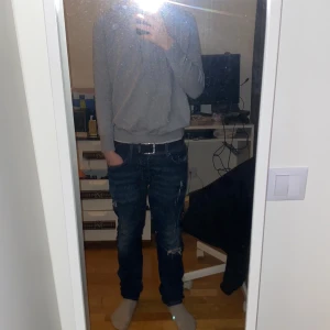 Grå merinoull hoodie - Säljer en stilren grå hoodie i merinoull med justerbar dragsko i huvan. Perfekt för en avslappnad look. Den har långa ärmar och ribbade muddar vid ärmslut och nederkant.