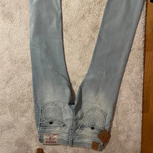 Ljusblå jeans från true religion - Snygga ljusblå jeans från true religion med klassisk femficksdesign och slitna detaljer. Märkeslappen syns tydligt baktill. Säljer pga inte passade mig! Aldrig används förutom testat om det passade 