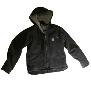 Svart jacka med huva från Carhartt - Säljer en svart jacka från Carhartt med huva och dragkedja. Jackan har en mysig fleecefodring och en bröstficka med dragkedja. Perfekt för kyliga dagar.
