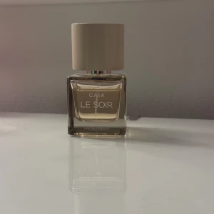 Le Soir Eau de Parfum från CAIA - Säljer en elegant parfymflaska från CAIA med doften Le Soir. Flaskan är fyrkantig och genomskinlig med en stilren beige kork. Perfekt för kvällar när du vill känna dig extra speciell. Flaskan är i nyskick och redo att användas! Pris 400:- 🫶🏽