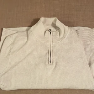 Vit halvzip från THESE GLORY DAYS - Säljer en stilren vit tröja från These Glory Days i storlek S. Tröjan är tillverkad av 100% ekologisk bomull och har en praktisk dragkedja framtill. Perfekt för en avslappnad och bekväm stil.