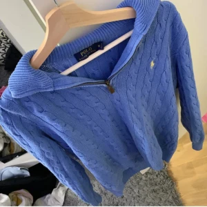 Blå stickad tröja från Polo Ralph Lauren - Säljer en snygg blå stickad tröja från Polo Ralph Lauren med dragkedja och kabelstickat mönster. Perfekt för kyligare dagar med sin stilrena design och bekväma passform. Tröjan har en liten fläck precis vid dragkedjan men går säkert väldigt enkelt bort, skriv om ni har några övriga frågor! Priset är inte hugget i sten!