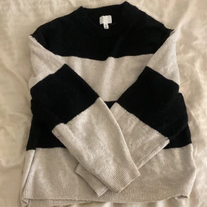 Randig tröja från H&M - Säljer en mysig randig tröja från H&M i svart och beige. Perfekt för höst och vinter med sin stickade design. Tröjan har långa ärmar och en normal passform. Superfin att matcha med jeans eller kjol. Den är också väldigt använd men är fortfarande jätte mysigt!