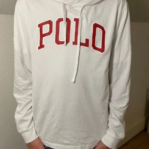 Vit hoodie från Polo - Säljer en snygg vit hoodie från Polo med röd text på bröstet. Den är i bra skick och perfekt för både vardag och chill. Stor luva och passar flera olika stilar. Hör av er vid några frågor!